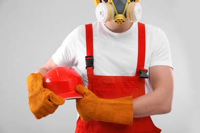 Photo of Male industrial worker in uniform on light background, closeup. Safety equipment