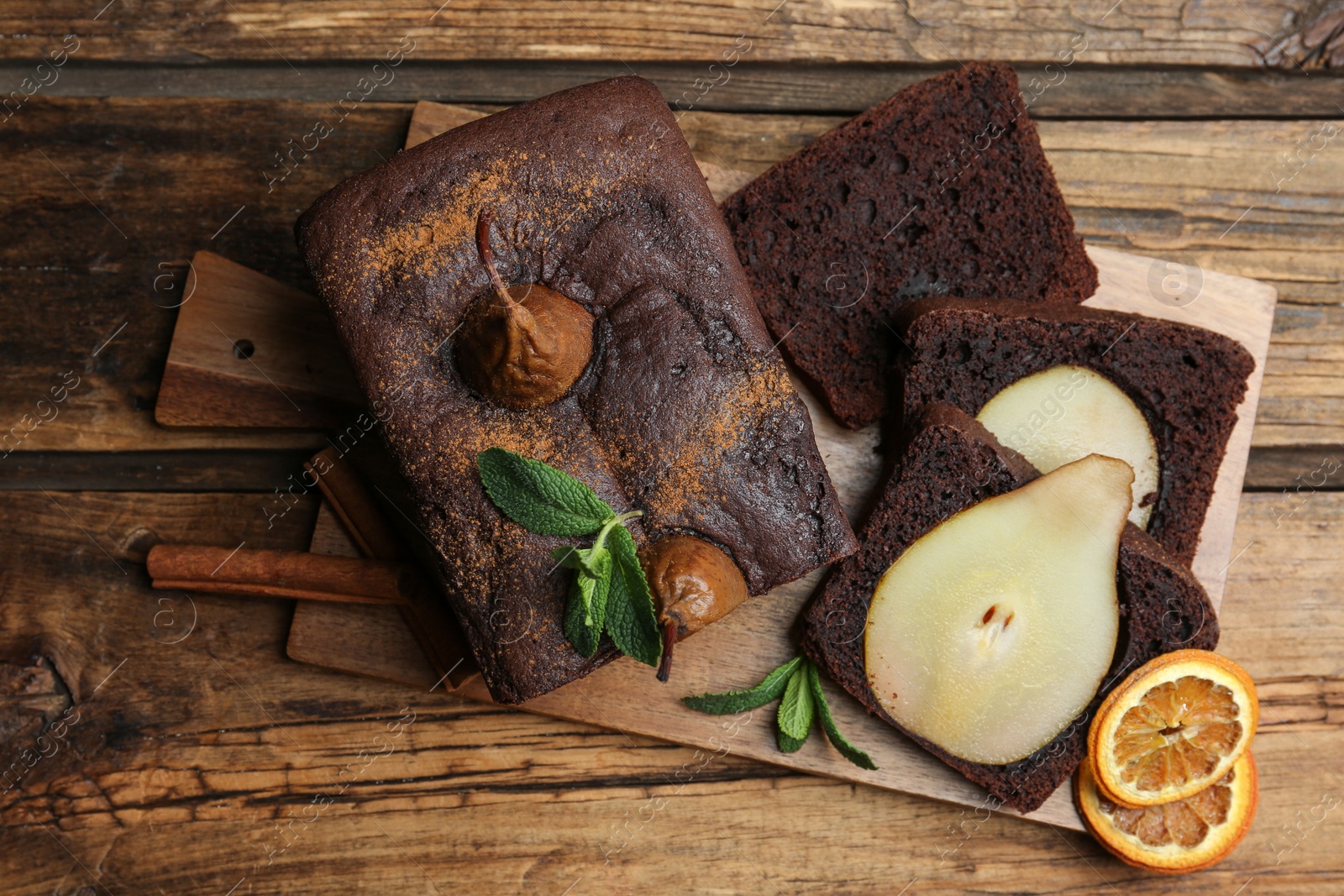 Photo of Tasty pear bread with mint, cinnamon and dried orange slices on wooden table, top view. Homemade cake