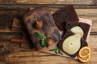 Photo of Tasty pear bread with mint, cinnamon and dried orange slices on wooden table, top view. Homemade cake