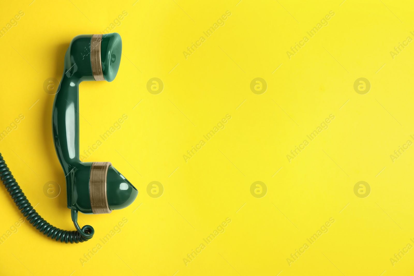 Photo of Handset of vintage green telephone on yellow background, top view. Space for text