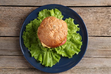 Photo of Delicious vegetarian burger on wooden table, top view