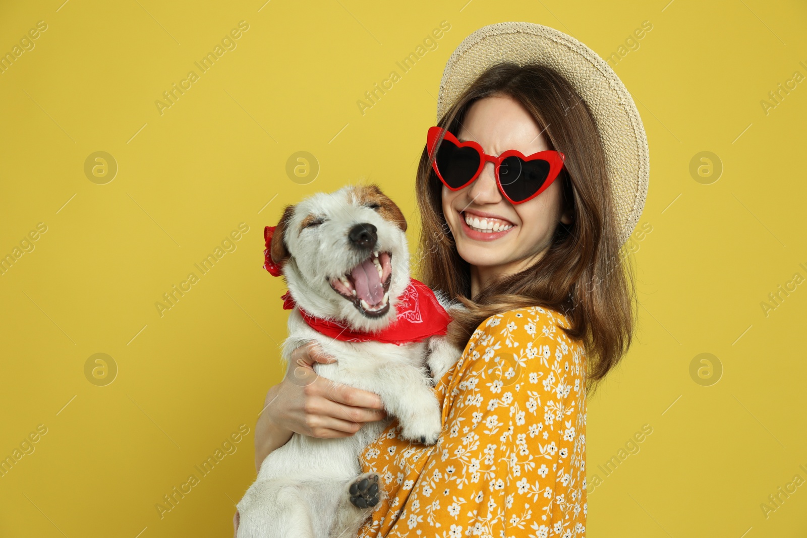 Photo of Young woman with her cute Jack Russell Terrier on yellow background. Lovely pet