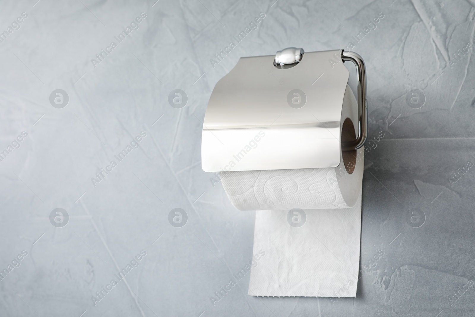 Photo of Holder with toilet paper roll on gray background. Space for text