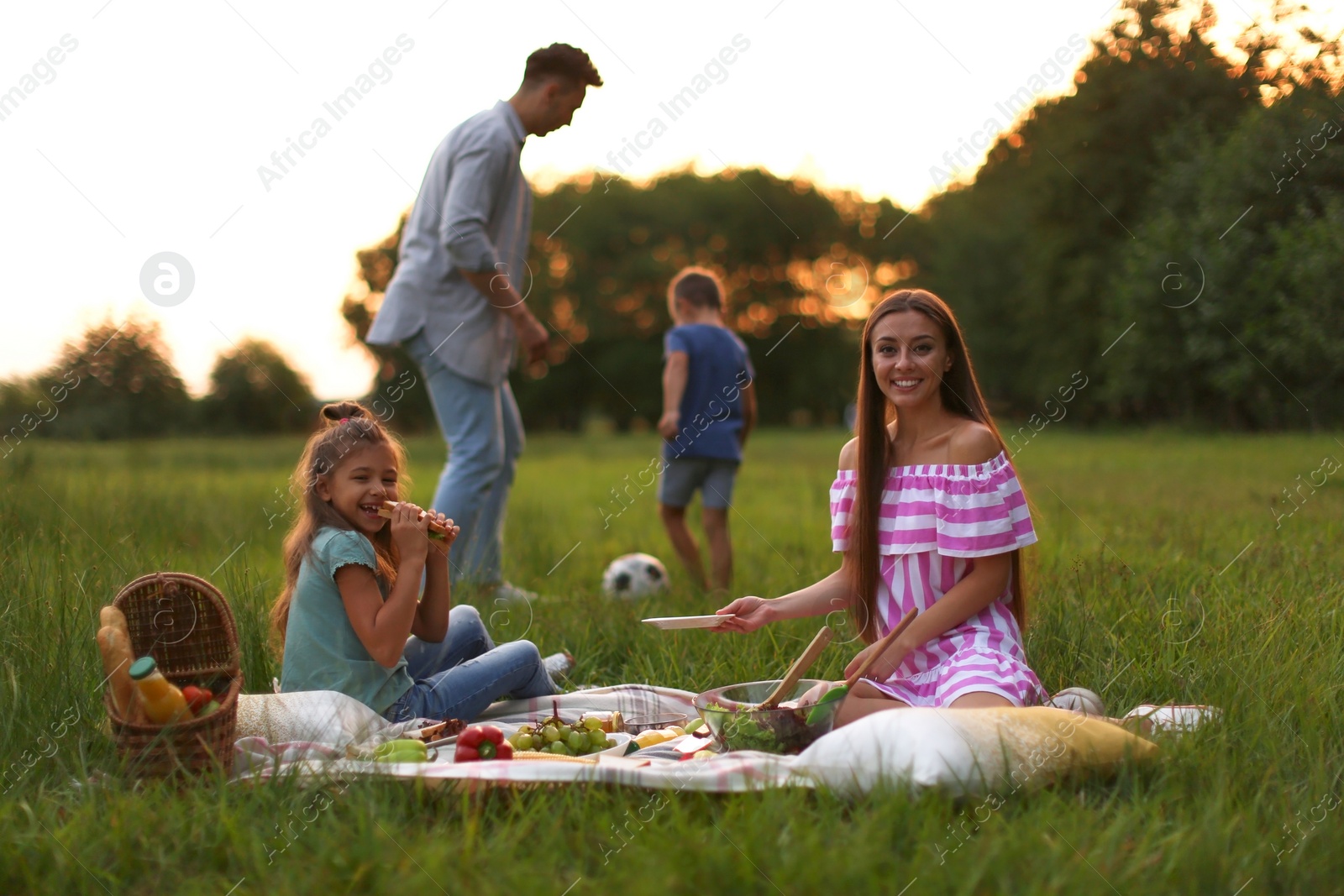 Photo of Happy family having picnic in park at sunset