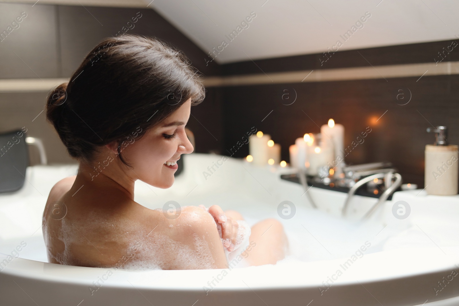 Photo of Happy beautiful woman taking bubble bath. Romantic atmosphere