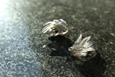 Elegant earrings on grey textured table, closeup