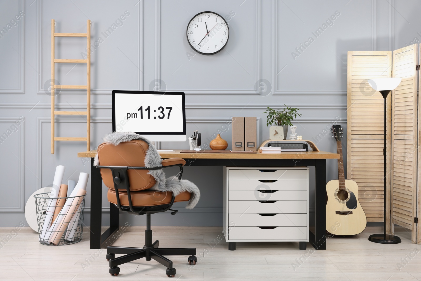 Photo of Stylish workplace with computer, houseplant and stationery on wooden desk near grey wall at home