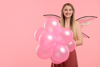 Beautiful girl in fairy costume with wings and balloons on pink background, space for text