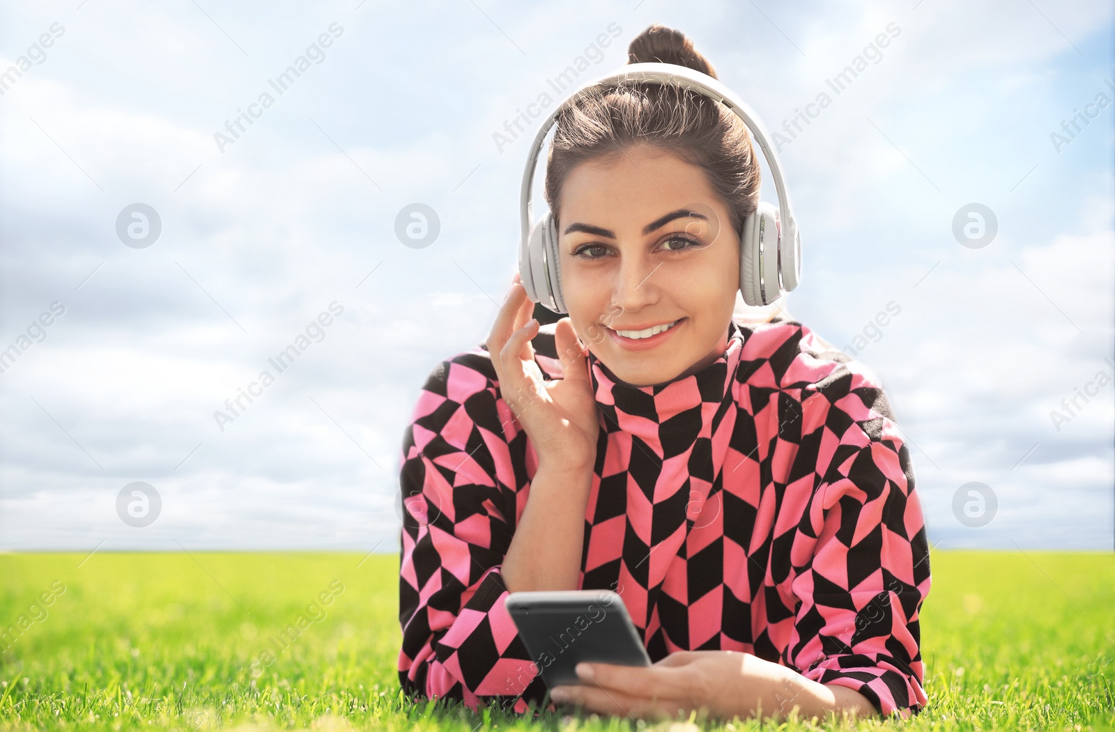 Photo of Young woman with headphones listening to music in park