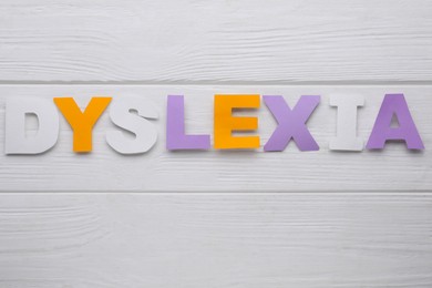 Photo of Word Dyslexia made of paper letters on white wooden background, flat lay
