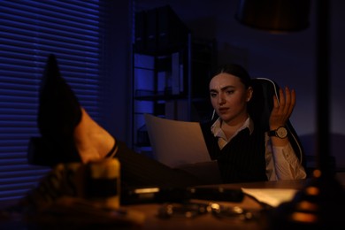 Photo of Professional detective working with documents at table in office at night
