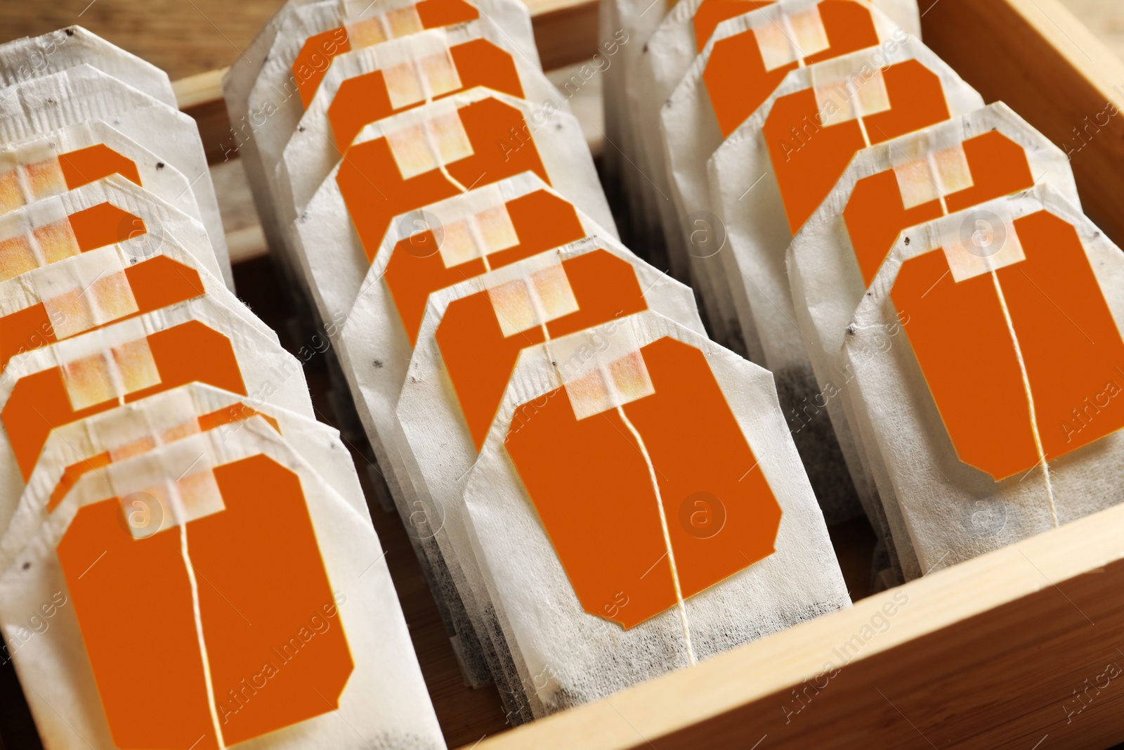 Photo of Paper tea bags with tags in wooden box, closeup