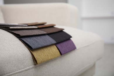 Photo of Catalog of colorful fabric samples on beige sofa, closeup