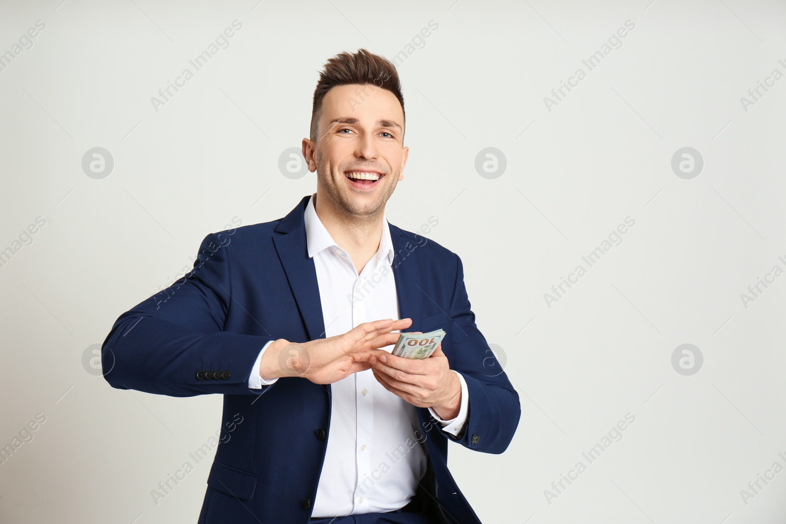 Photo of Happy man throwing money on light grey background. Space for text