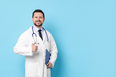 Photo of Doctor with clipboard showing thumbs up against light blue background. Space for text