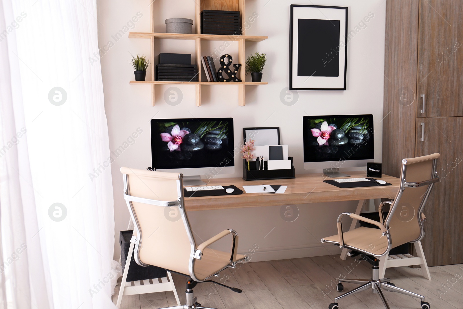 Photo of Modern workplace with large desk and computers in room. Stylish interior