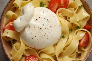 Photo of Bowl of delicious pasta with burrata and tomatoes, closeup
