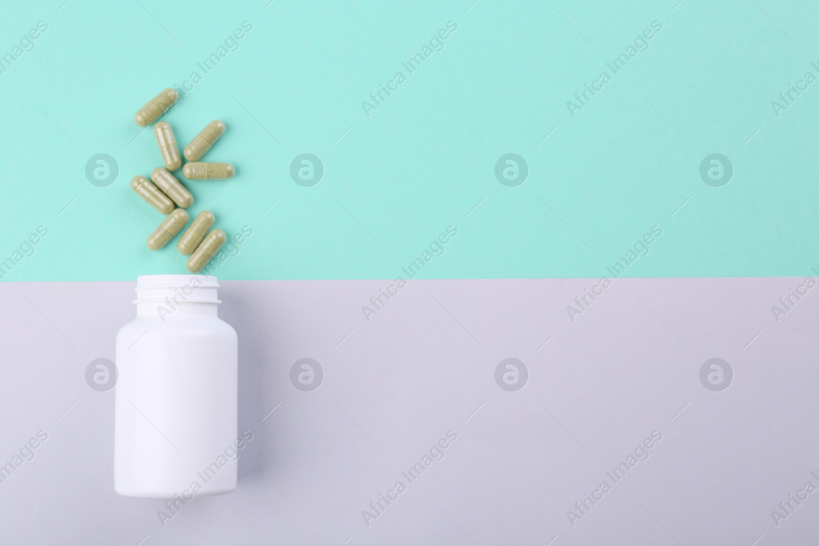 Photo of Bottle and vitamin capsules on color background, top view. Space for text