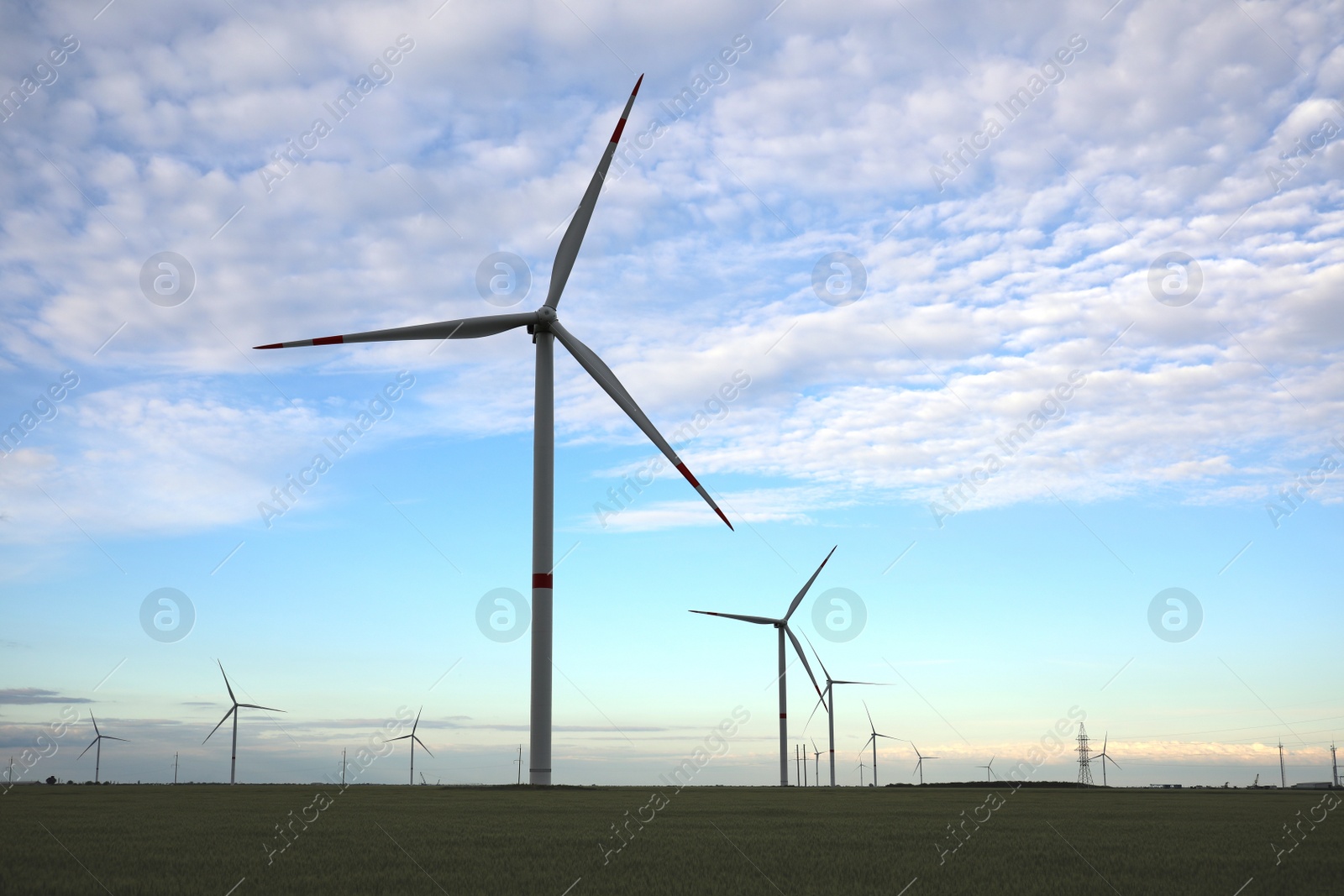 Photo of Beautiful view of field with wind turbines in evening. Alternative energy source