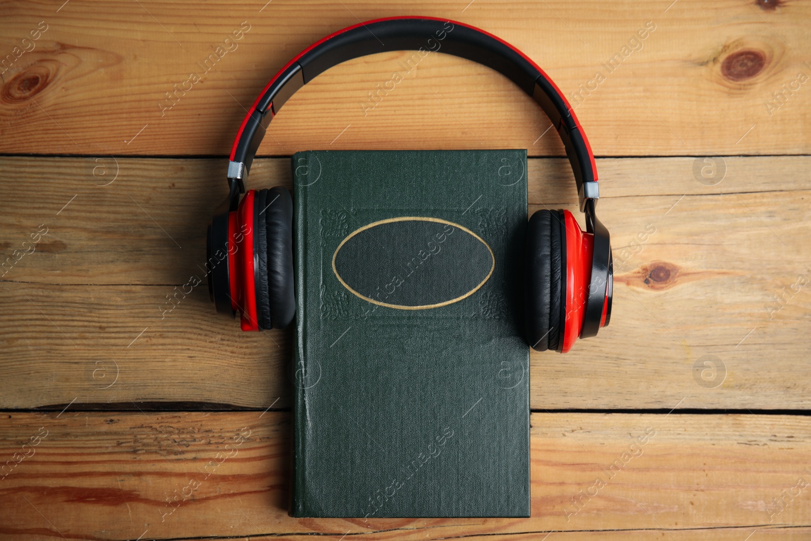 Photo of Book and modern headphones on wooden table, top view