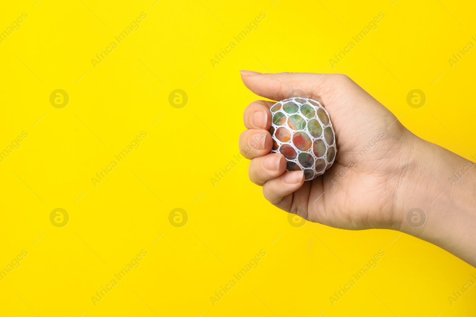 Photo of Woman holding colorful slime on yellow background, closeup. Antistress toy