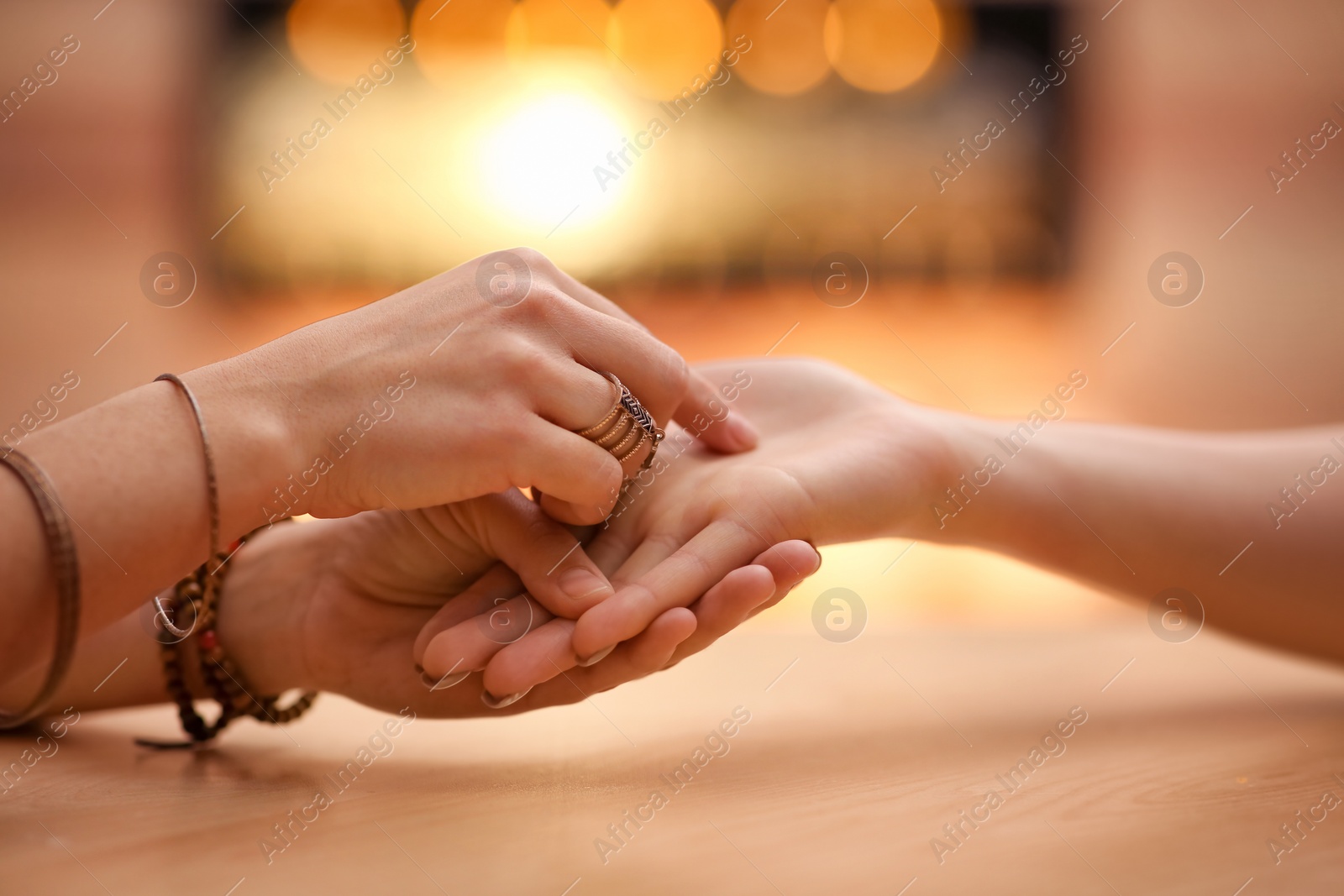 Photo of Chiromancer reading lines on woman's palm at table, closeup