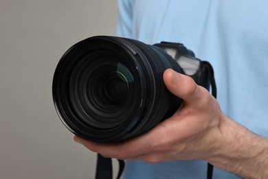 Photo of Photographer holding camera on grey background, closeup