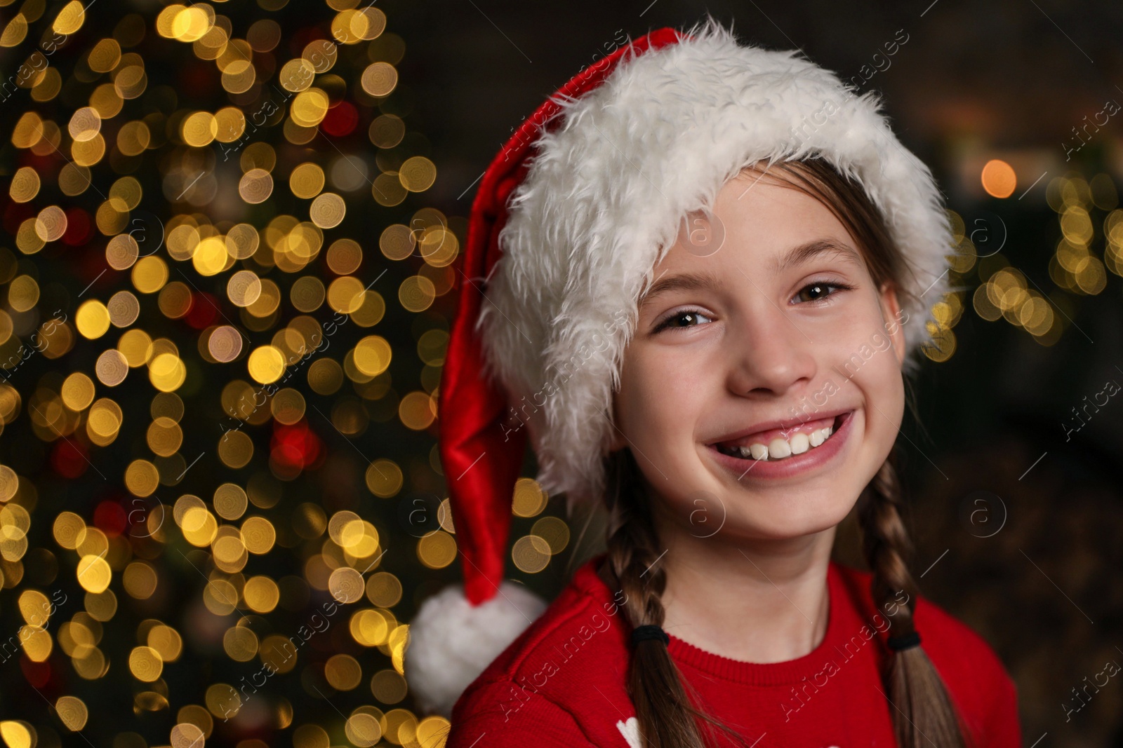 Photo of Portrait of happy child wearing Santa hat indoors. Christmas time
