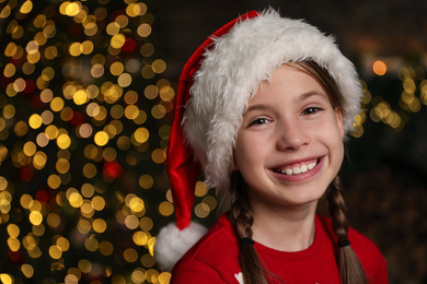 Photo of Portrait of happy child wearing Santa hat indoors. Christmas time