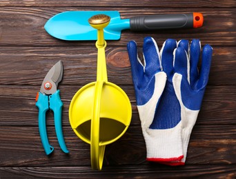 Photo of Flat lay composition with watering can and gardening tools on wooden table