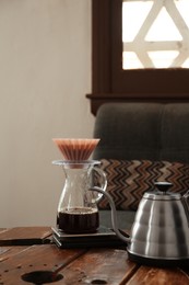 Photo of Jug of coffee with wave dripper and kettle on wooden table in cafe