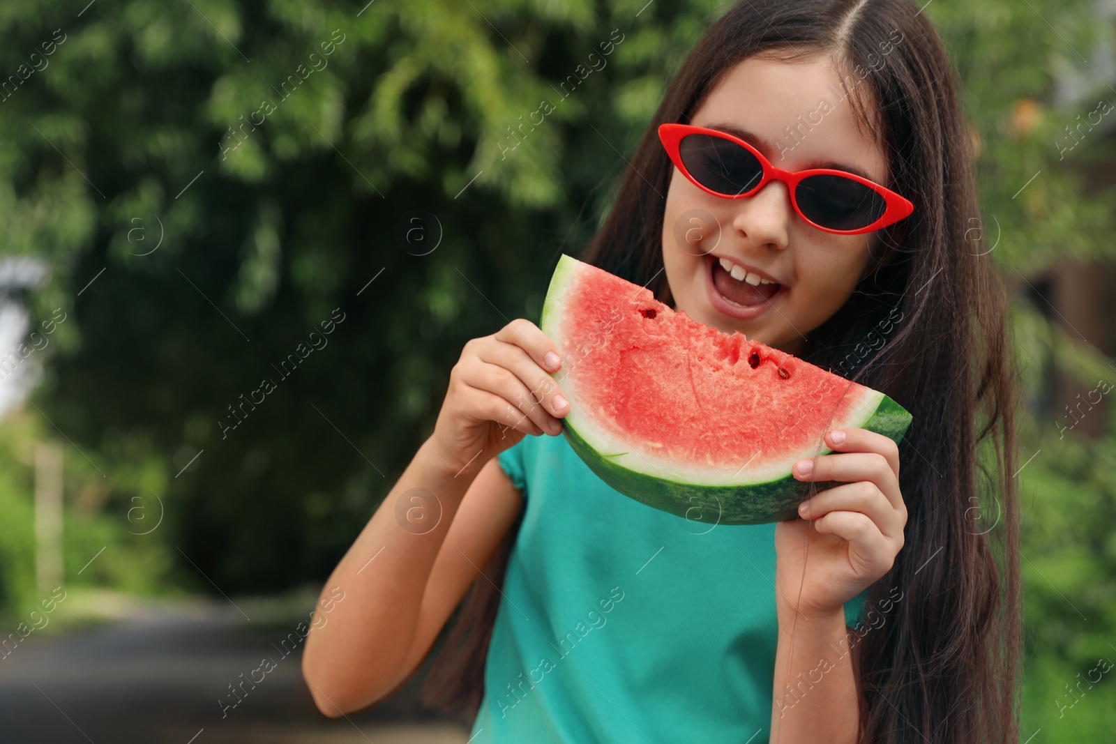 Photo of Cute little girl with watermelon outdoors on sunny day