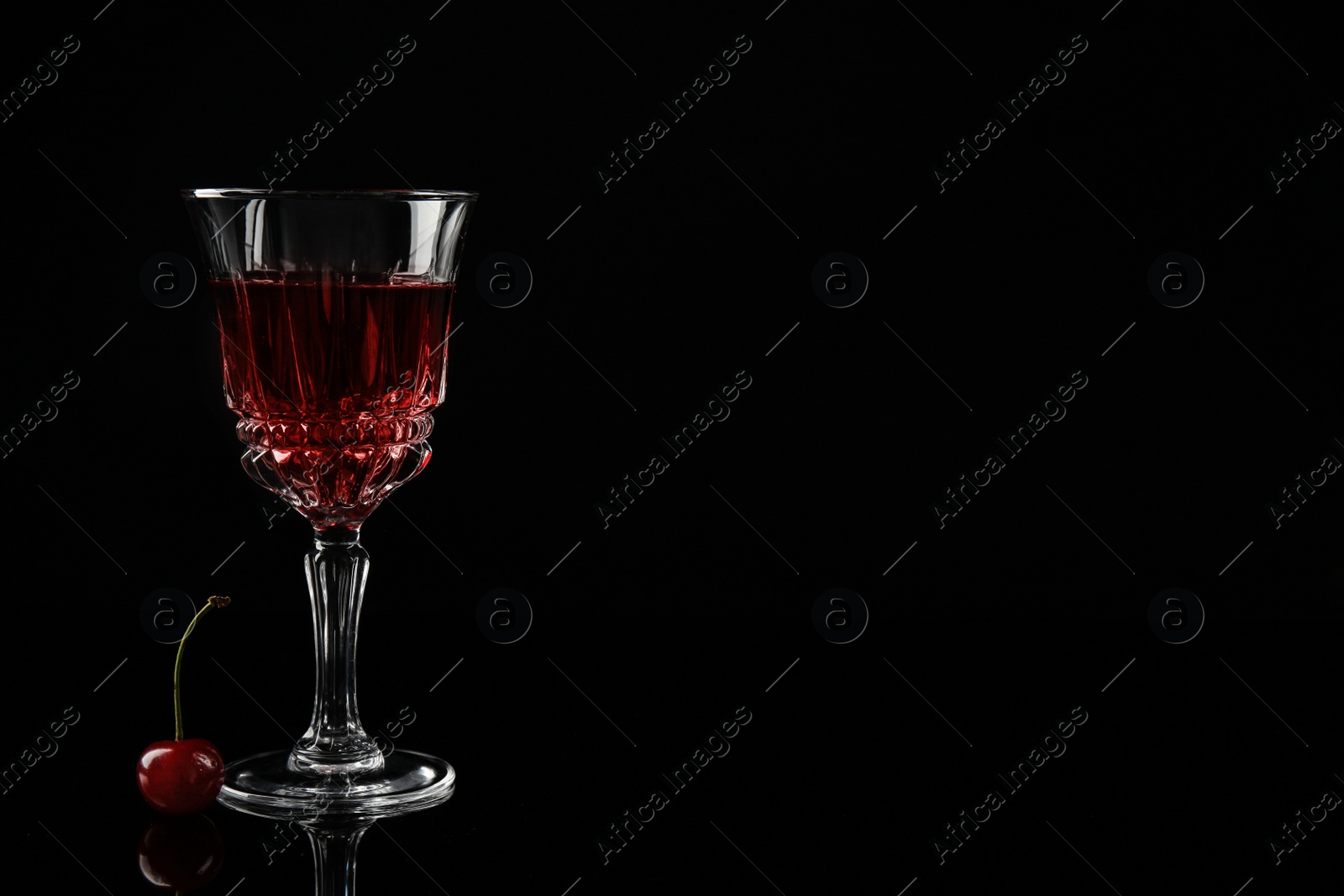 Photo of Delicious cherry wine with ripe juicy berries on black background. Space for text