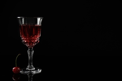 Delicious cherry wine with ripe juicy berries on black background. Space for text
