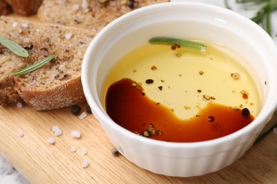 Photo of Bowl of organic balsamic vinegar with oil, bread slices and spices on wooden board, closeup