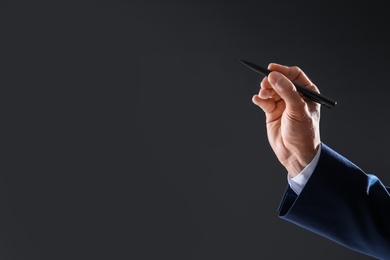Photo of Businessman holding pen in hand on dark background