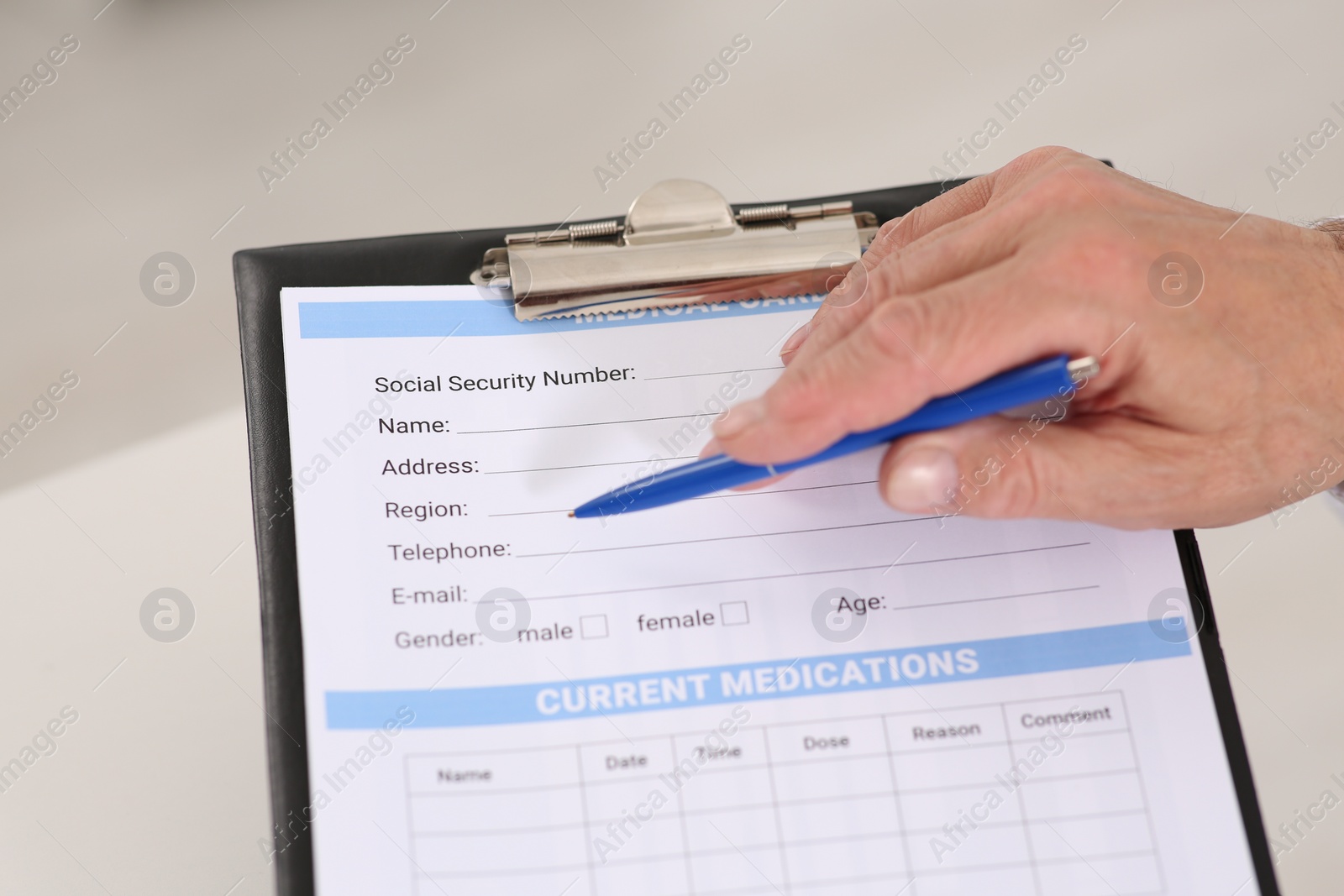 Photo of Doctor with patient's medical card at table in clinic, closeup