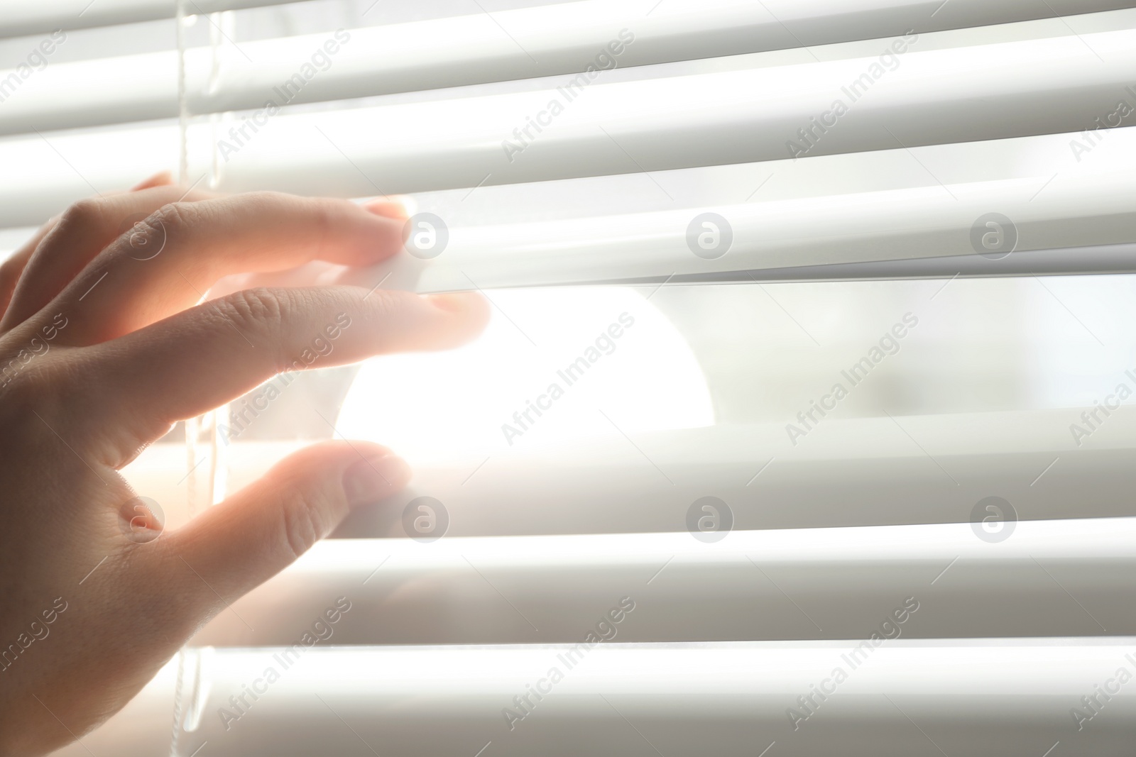 Photo of Woman opening horizontal window blinds at home, closeup. Space for text