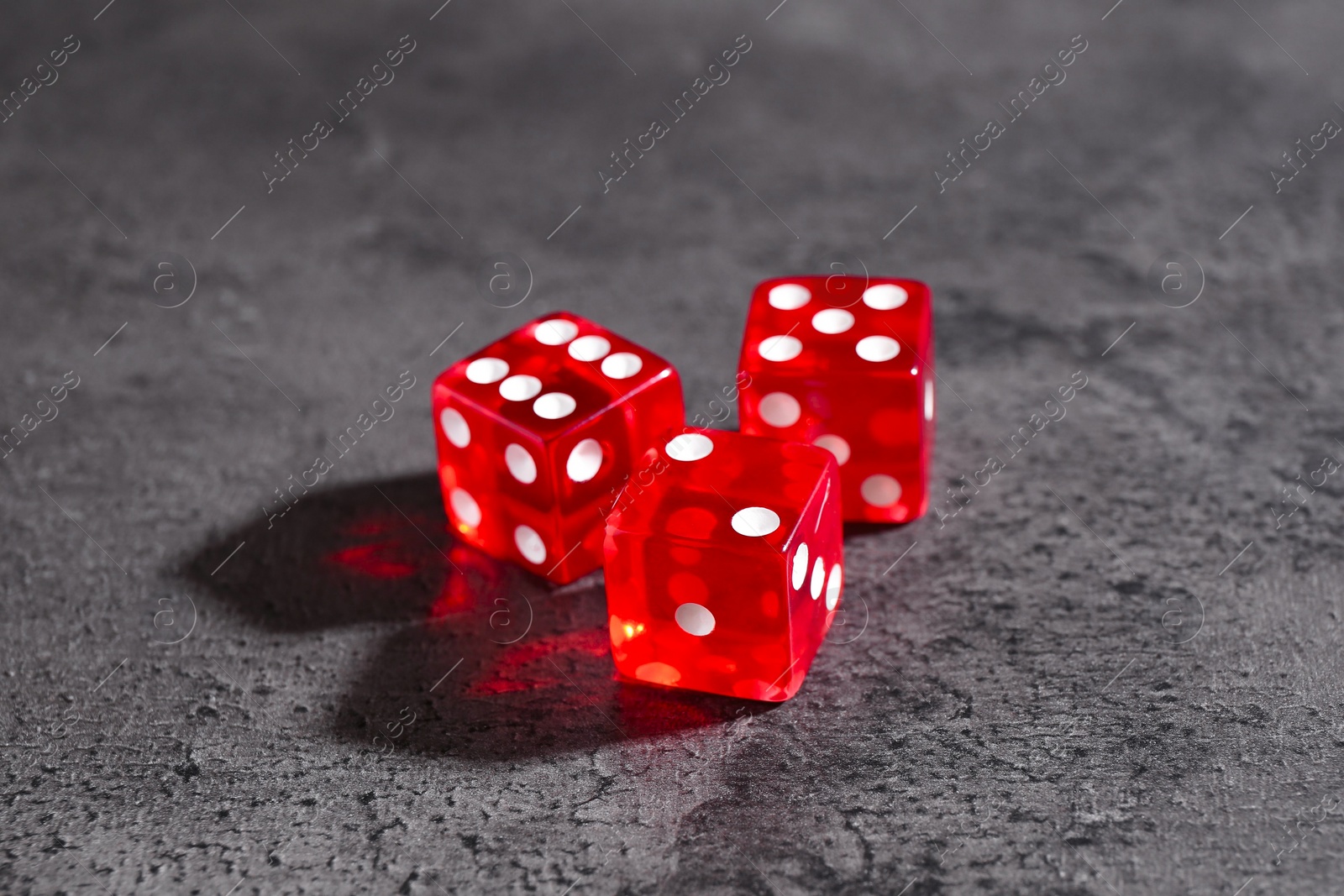 Photo of Three red game dices on grey textured table