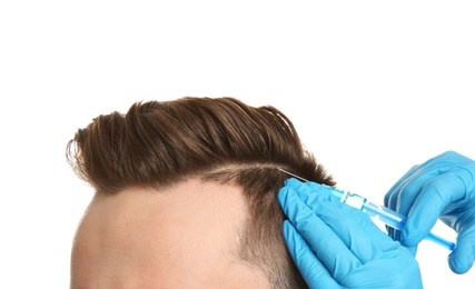 Young man with hair loss problem receiving injection on white background, closeup