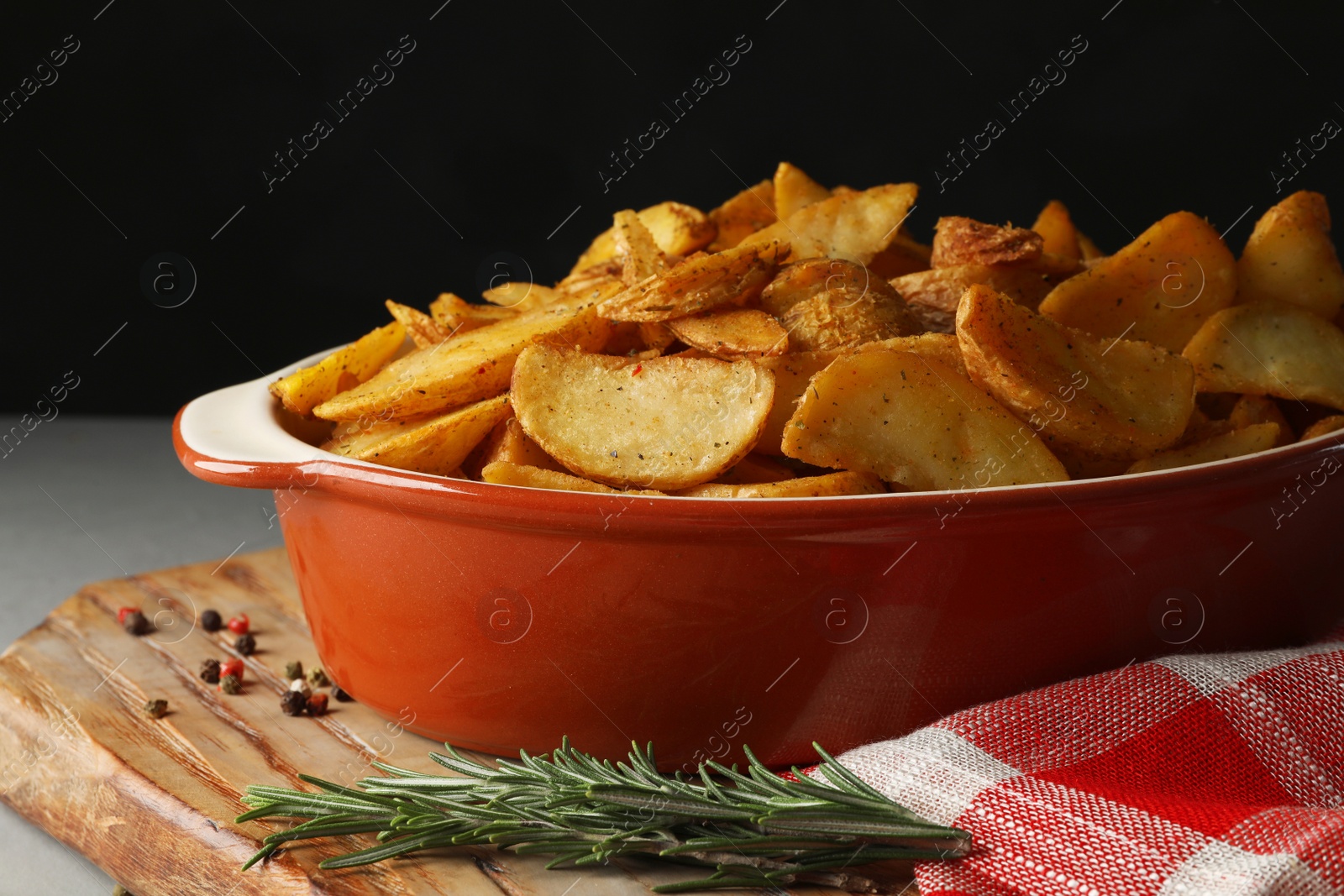 Photo of Dish of delicious oven baked potatoes on table, closeup