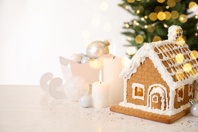 Beautiful gingerbread house decorated with icing and candles on white table