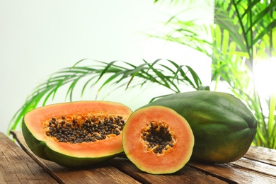 Fresh juicy papayas on wooden table against blurred background, space for text