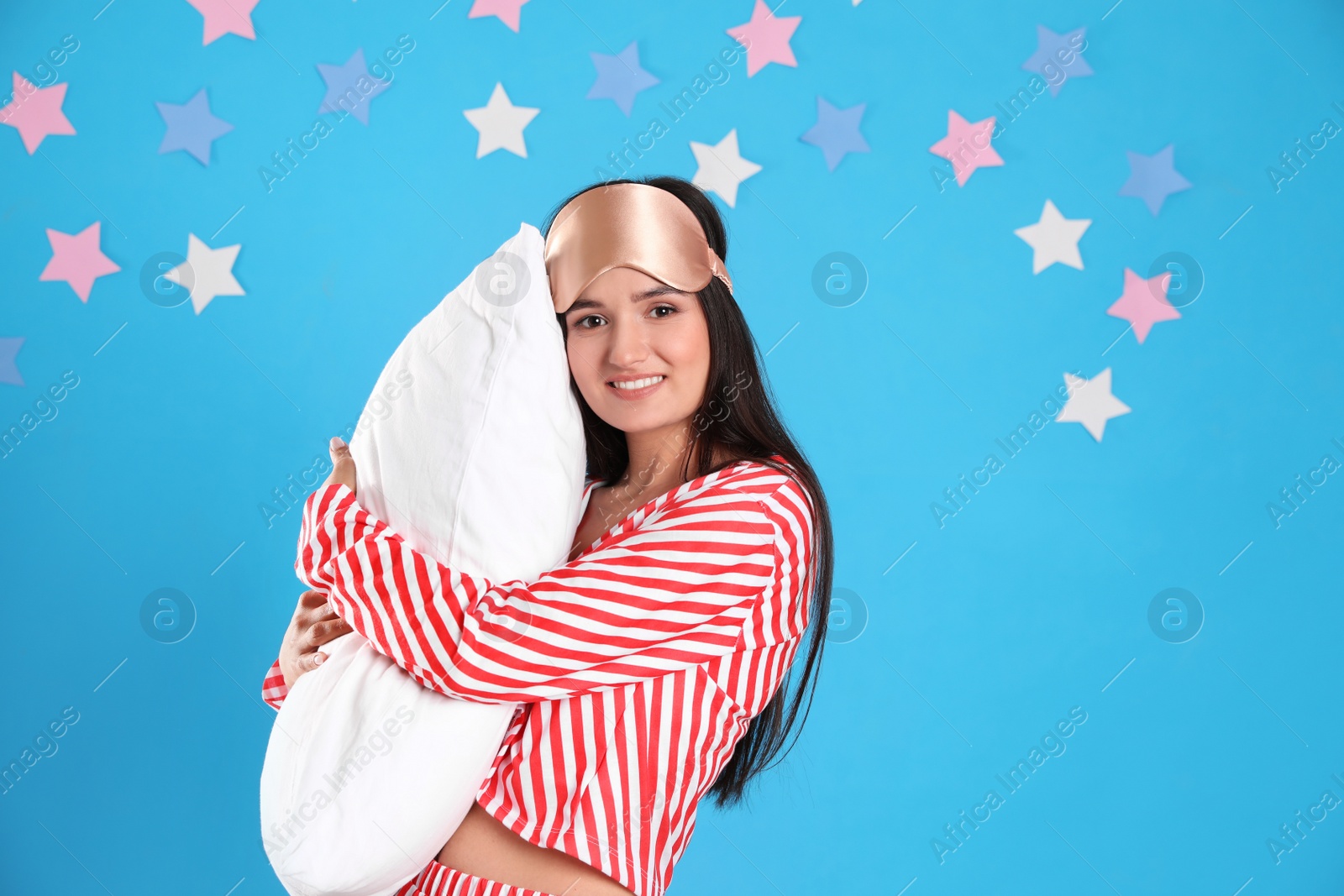 Photo of Beautiful woman with pillow on light blue background. Bedtime