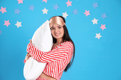 Beautiful woman with pillow on light blue background. Bedtime