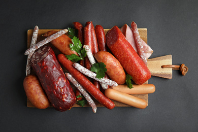 Photo of Different types of sausages served on black background, top view