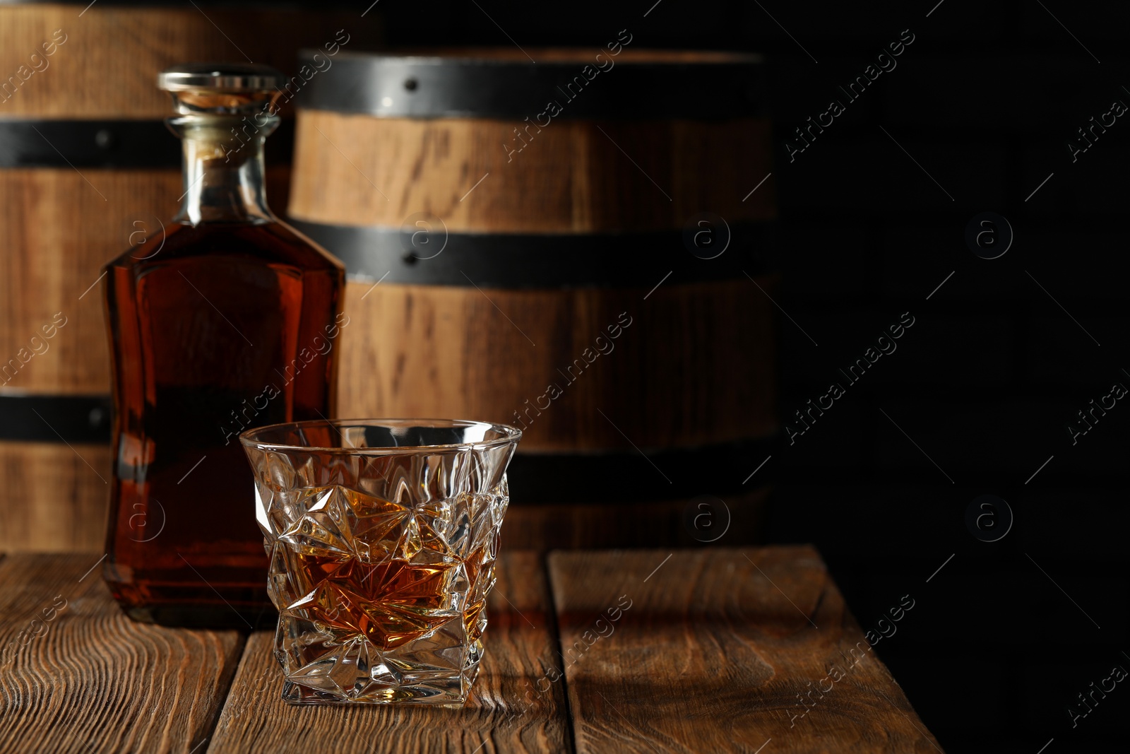 Photo of Glass and bottle of tasty whiskey on wooden table. Space for text