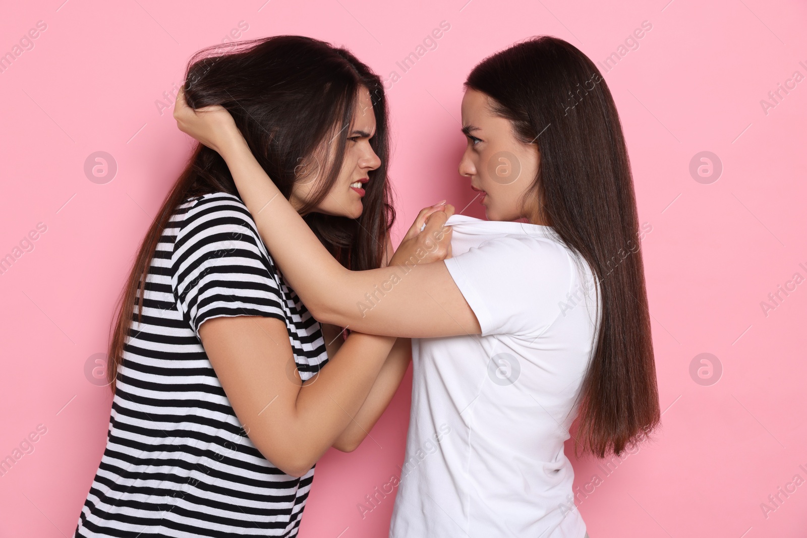 Photo of Aggressive young women fighting on pink background