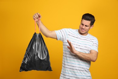 Man holding full garbage bag on yellow background