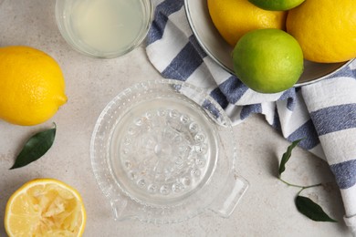 Photo of Glass squeezer with juice and lemons on light table, flat lay